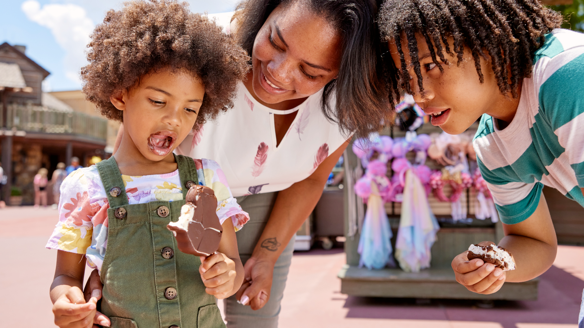 Little girl eating Mickey ice cream bar with her family