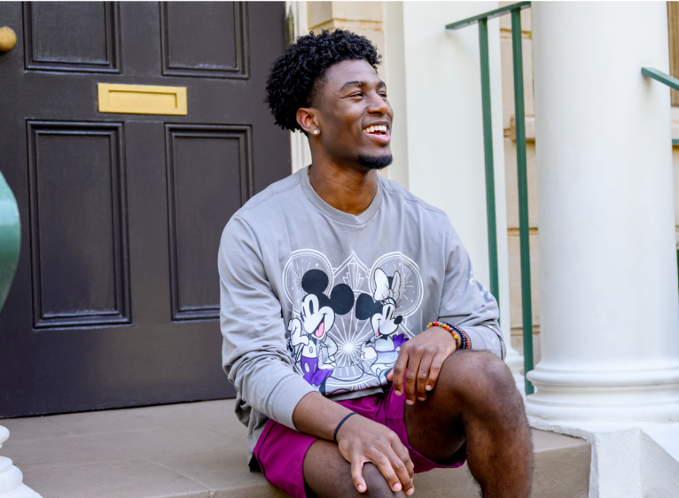 Man smiling wearing Disney100 sweatshirt